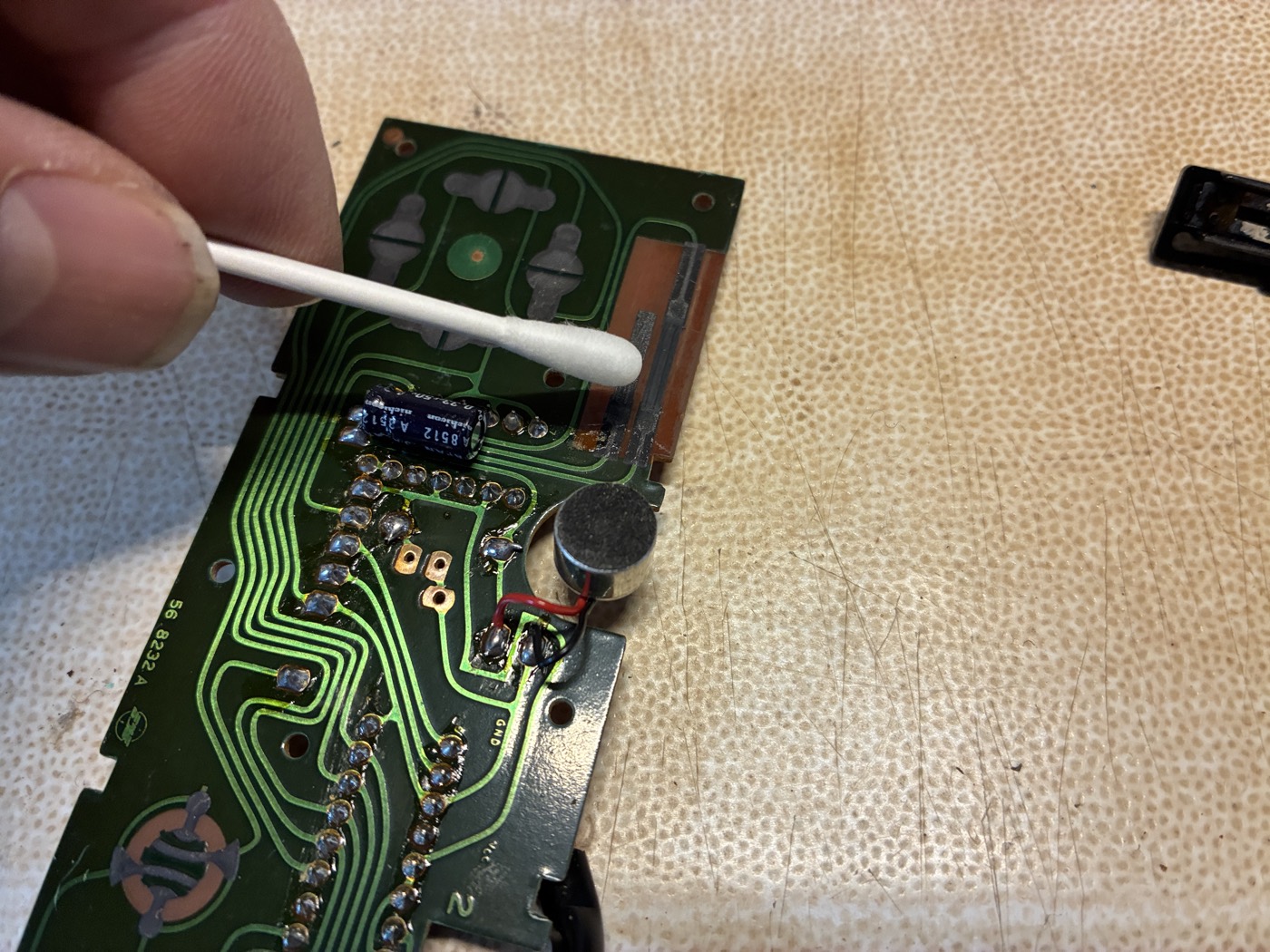 Cleaning the microphone's two lead wires and solder pads with ethanol on a cotton swab
